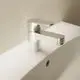 Waschtischarmatur aus Chrom von Ideal Standard mit einem Hebel und Metall-Ablaufgarnitur, montiert auf einer weißen Oberfläche neben einem Waschbecken.